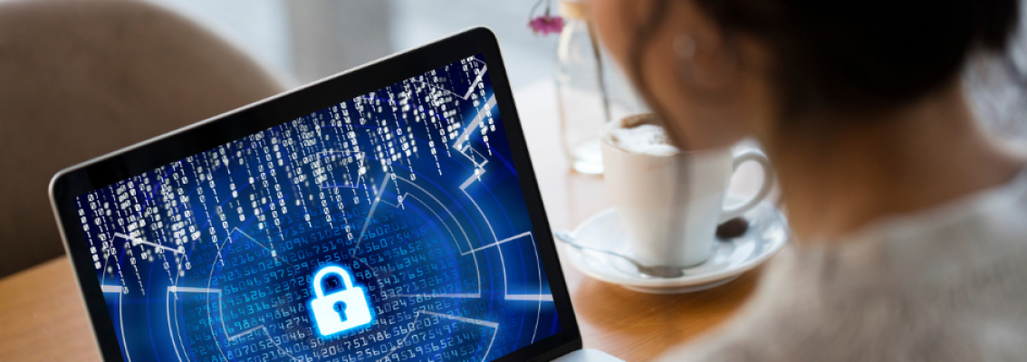 A woman is looking at her computer screen. The screen shows the icon of a lock, symbolizing a hacked website.