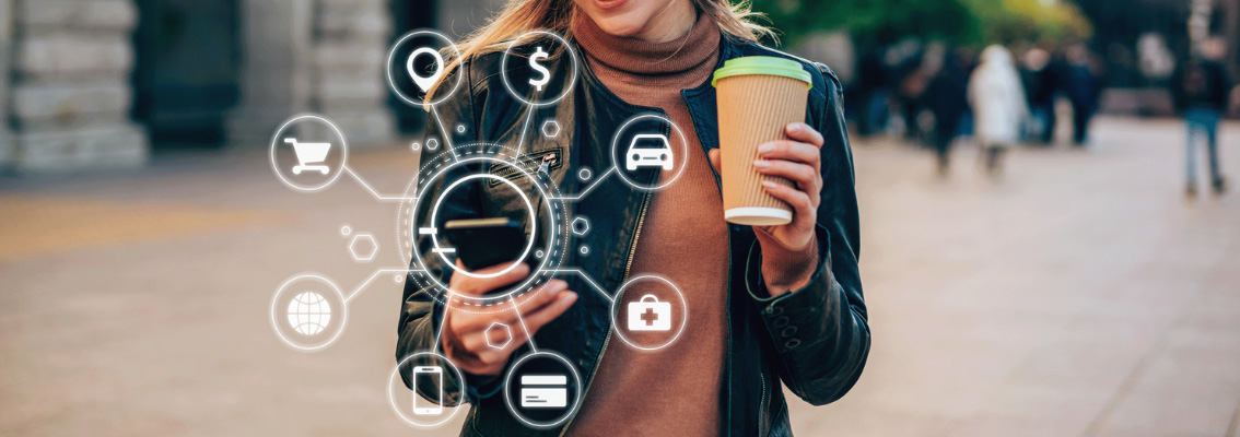A woman is using her smartphone. Around the phone are some icons that represent shopping, information, contact, address, payment and transportation.
