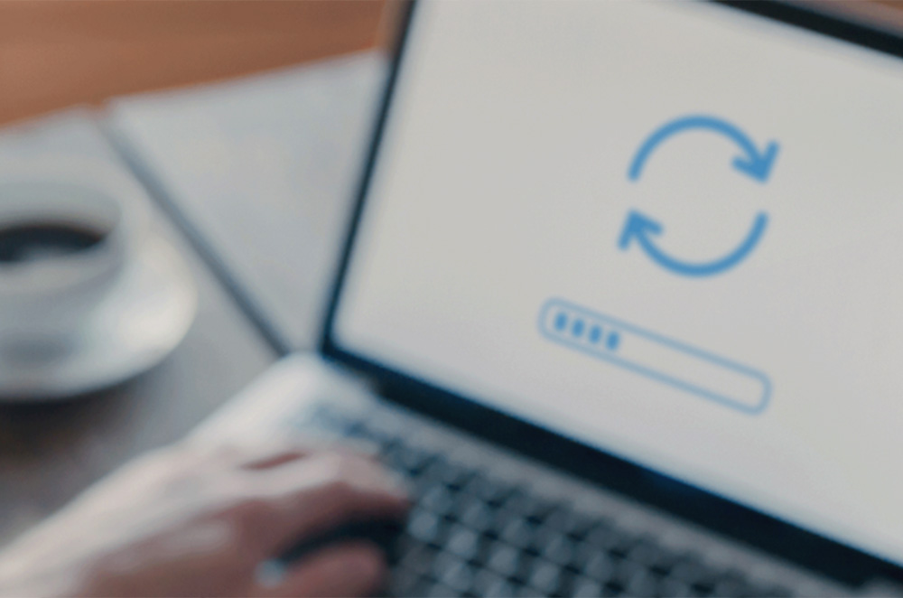 A person looking at a computer screen. The screen shows an “update” symbol.